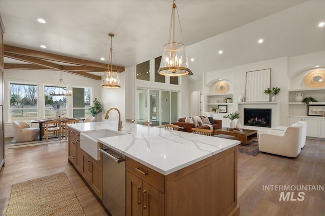 kitchen with stainless steel dishwasher, vaulted ceiling with beams, wood finished floors, and a sink