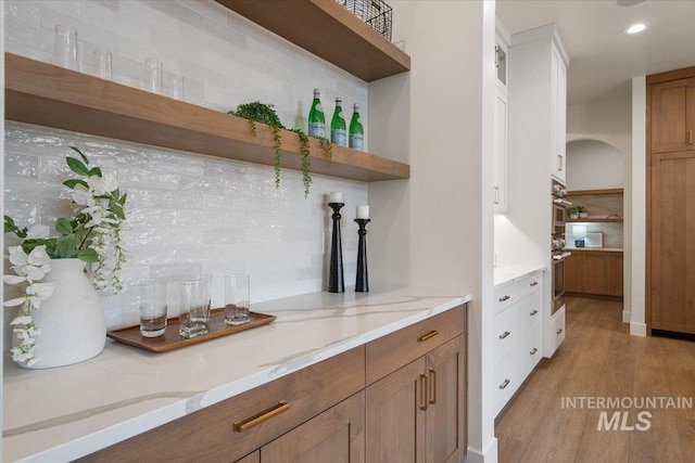 bar with recessed lighting, backsplash, and light wood-style flooring