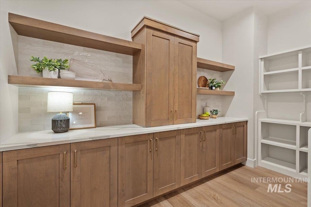 kitchen featuring open shelves, brown cabinets, tasteful backsplash, and light wood-type flooring