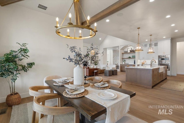 dining room featuring visible vents, a notable chandelier, vaulted ceiling with beams, and light wood finished floors