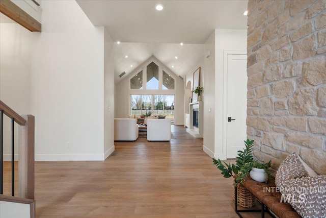 corridor with visible vents, baseboards, light wood finished floors, high vaulted ceiling, and recessed lighting