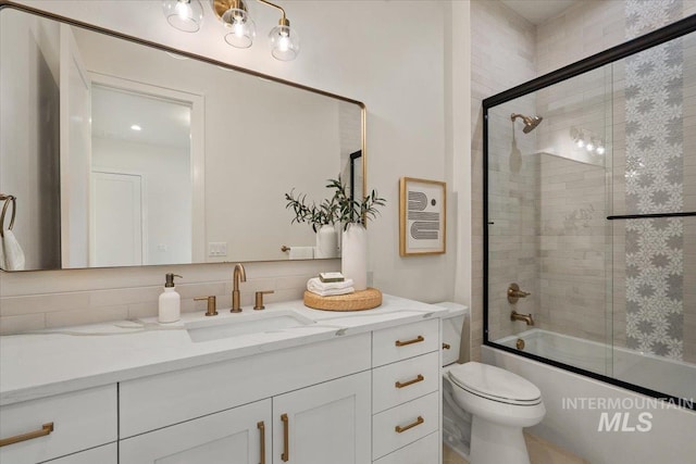 full bath with vanity, toilet, and bath / shower combo with glass door