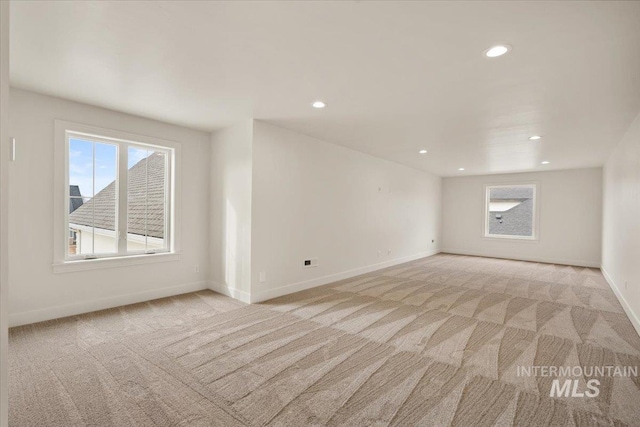 spare room with recessed lighting, baseboards, and light carpet