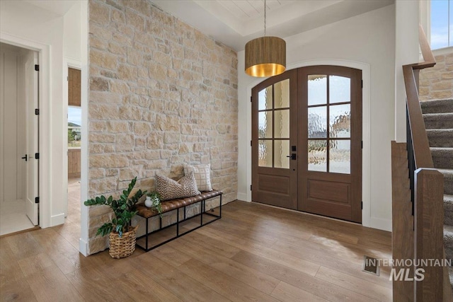 entryway featuring wood finished floors, stairway, french doors, and arched walkways