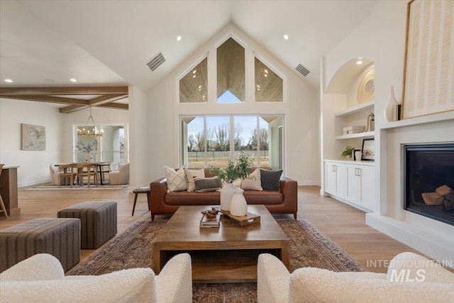 living area with light wood-style flooring, built in features, visible vents, and a chandelier