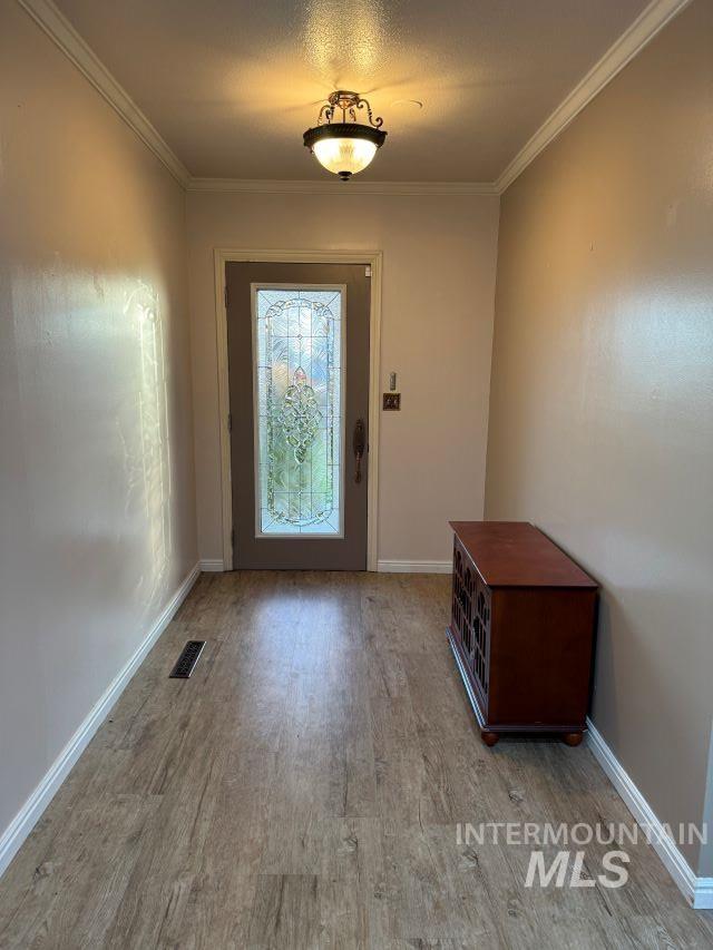 entryway with wood-type flooring and ornamental molding