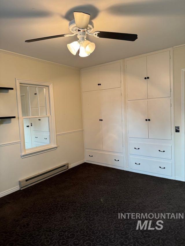 unfurnished bedroom with ceiling fan, dark carpet, crown molding, and baseboard heating