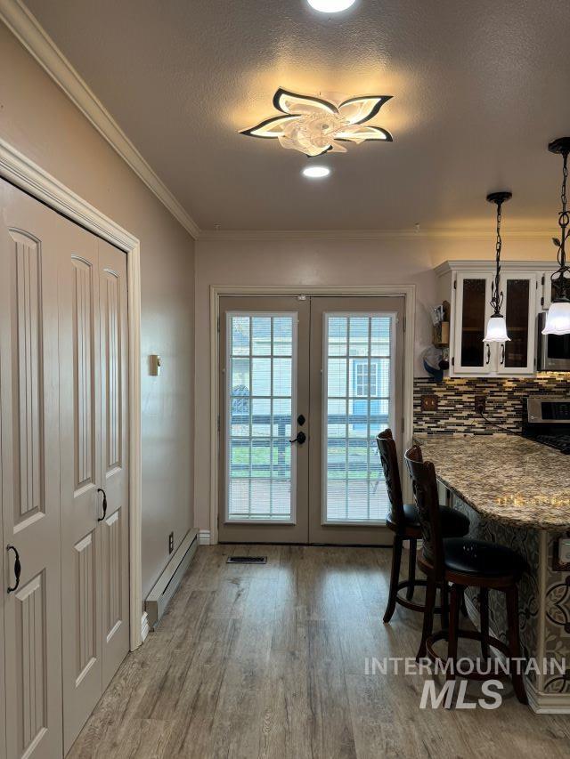 entryway with french doors, a textured ceiling, crown molding, a baseboard radiator, and hardwood / wood-style floors