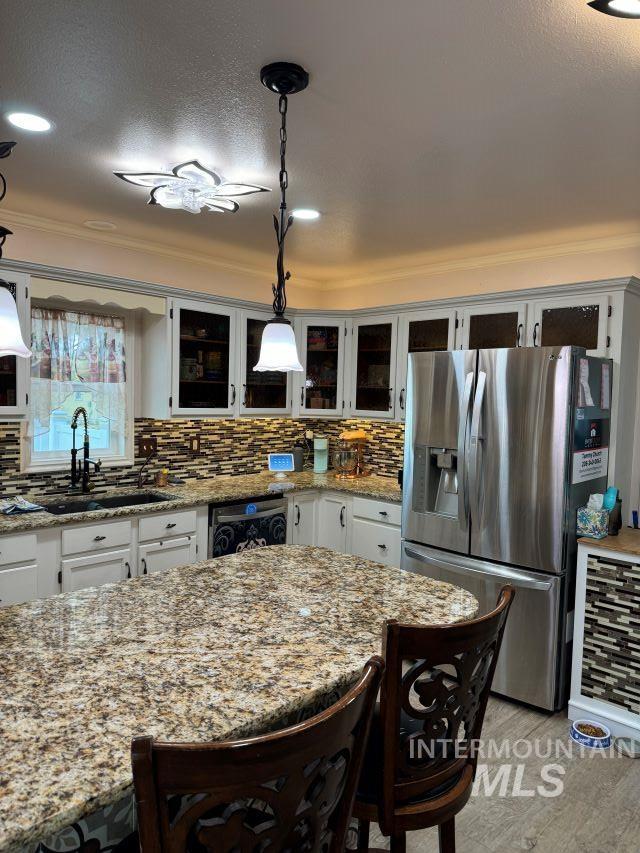 kitchen featuring white cabinetry, stainless steel fridge with ice dispenser, sink, and decorative light fixtures