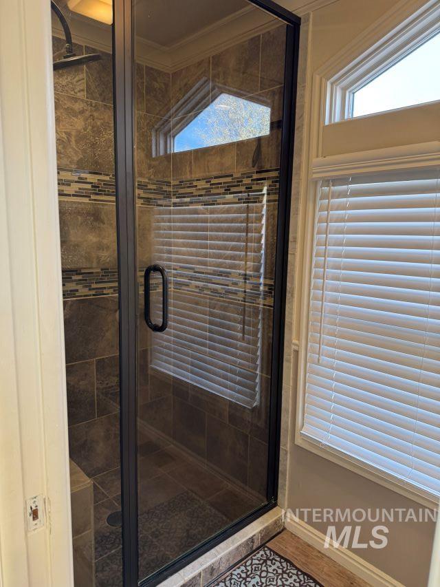 bathroom with an enclosed shower and ornamental molding