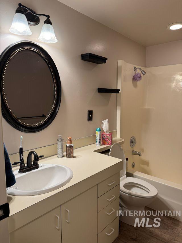 full bathroom featuring hardwood / wood-style floors, vanity, bathtub / shower combination, and toilet