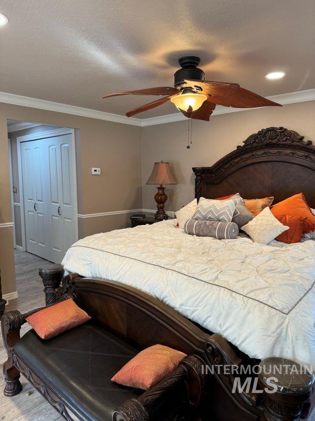 bedroom featuring ceiling fan, a closet, crown molding, and a textured ceiling