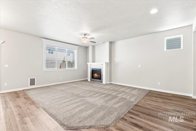 4084 E Blueberry St, Meridian, ID 83642 - unfurnished living room featuring ceiling fan, wood finished floors, a warm lit fireplace, a textured ceiling, and baseboards