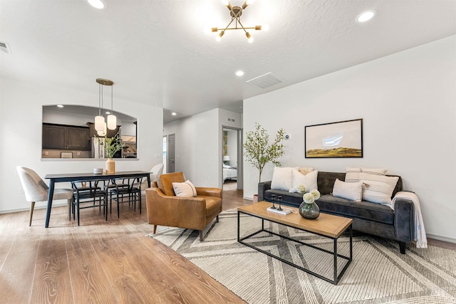 living area with visible vents, recessed lighting, light wood-style floors, and an inviting chandelier