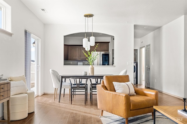 dining room featuring visible vents, baseboards, washer / dryer, and wood finished floors