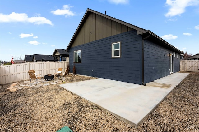 rear view of property with a patio, a fire pit, board and batten siding, and a fenced backyard