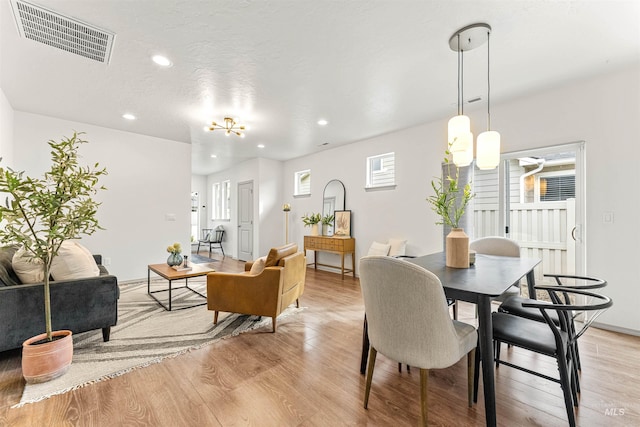 dining room with light wood finished floors, visible vents, recessed lighting, and an inviting chandelier