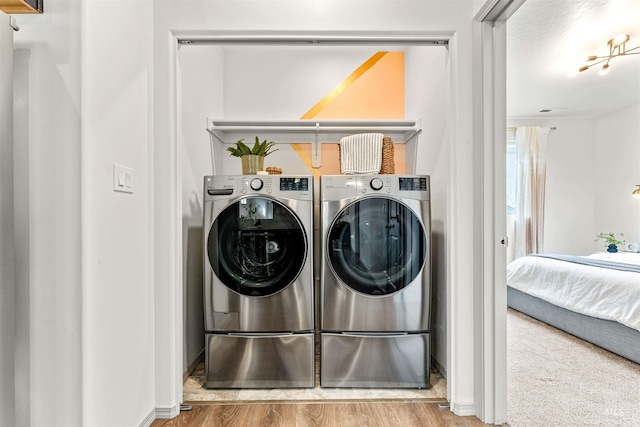 clothes washing area featuring washing machine and dryer and wood finished floors