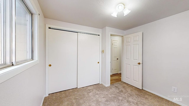 unfurnished bedroom with light carpet and a closet