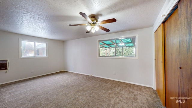 unfurnished bedroom featuring heating unit, ceiling fan, a textured ceiling, carpet floors, and a closet