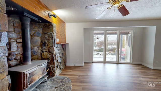 unfurnished living room with a wood stove, ceiling fan, and a healthy amount of sunlight