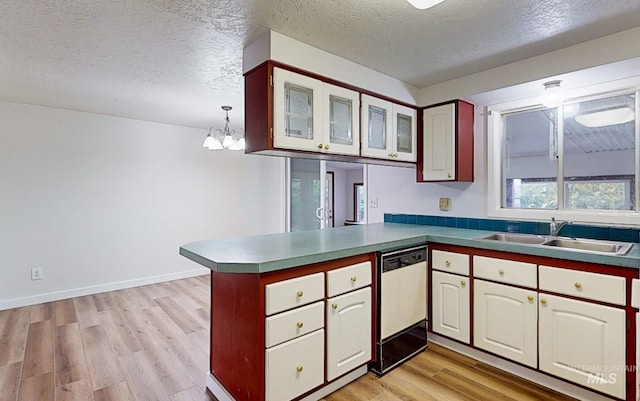 kitchen featuring sink, black dishwasher, kitchen peninsula, pendant lighting, and a textured ceiling