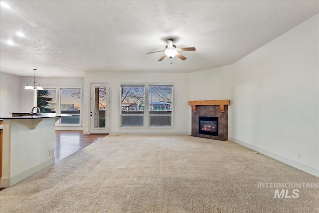 1280 W Bacall St, Meridian, ID 83646 - unfurnished living room with a textured ceiling, baseboards, a fireplace, carpet, and ceiling fan with notable chandelier