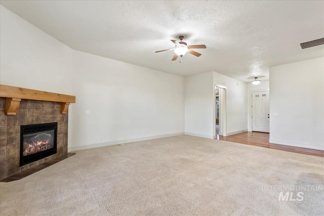 1280 W Bacall St, Meridian, ID 83646 - unfurnished living room featuring a tiled fireplace, carpet floors, ceiling fan, baseboards, and visible vents