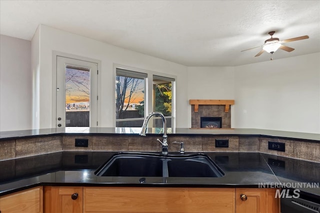 1280 W Bacall St, Meridian, ID 83646 - kitchen featuring a tile fireplace, a sink, black dishwasher, ceiling fan, and dark countertops