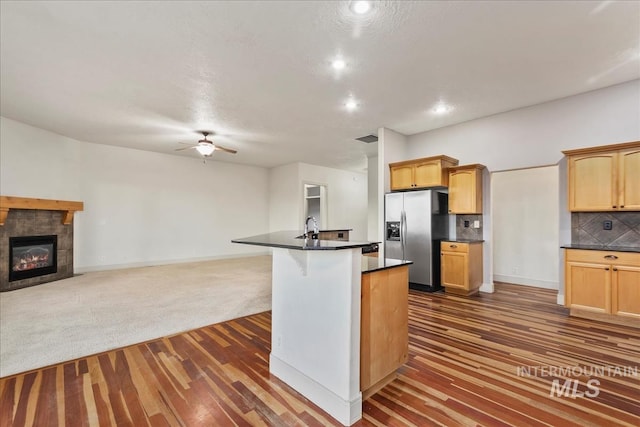 1280 W Bacall St, Meridian, ID 83646 - kitchen with a fireplace, stainless steel refrigerator with ice dispenser, dark countertops, and a ceiling fan