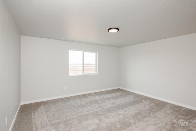 carpeted empty room featuring a textured ceiling