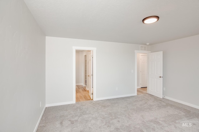 unfurnished room with light colored carpet and a textured ceiling