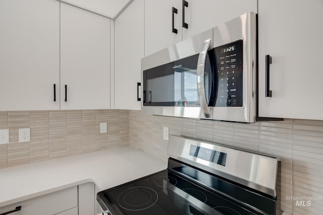 kitchen with backsplash, stainless steel appliances, and white cabinets