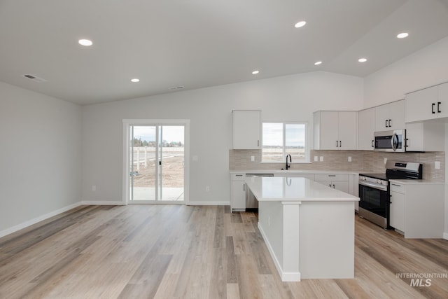 kitchen featuring stainless steel appliances, sink, a kitchen island, and white cabinets