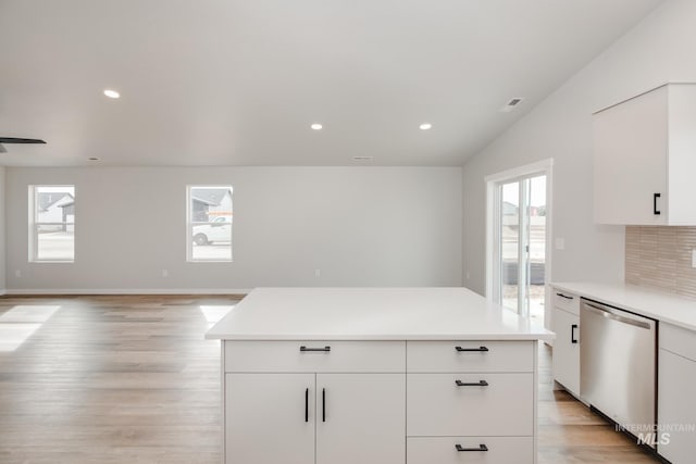 kitchen featuring stainless steel dishwasher, a wealth of natural light, a center island, and white cabinets