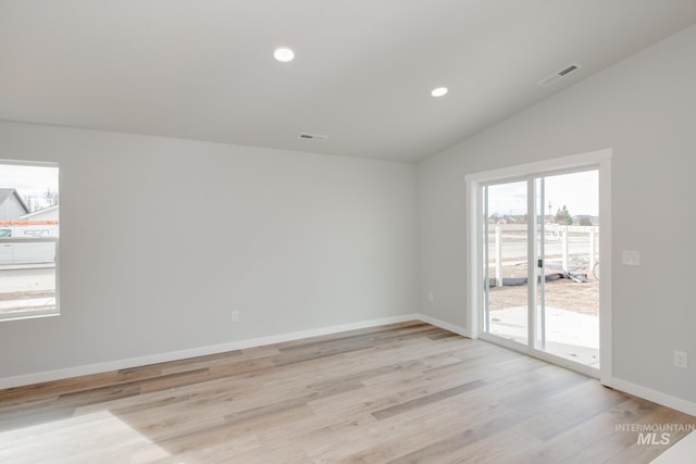 unfurnished room with lofted ceiling and light wood-type flooring