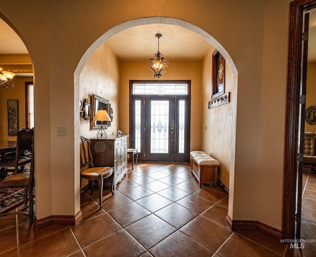 186 Ridgeview Dr, Grangeville, ID 83530 - entrance foyer with a notable chandelier, baseboards, a textured wall, arched walkways, and dark tile patterned flooring
