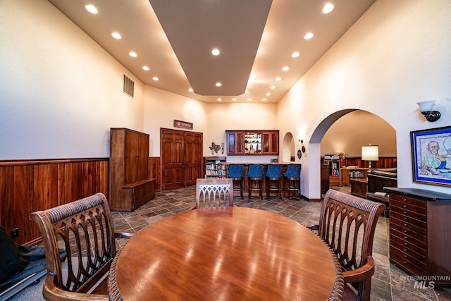 186 Ridgeview Dr, Grangeville, ID 83530 - dining area with visible vents, arched walkways, wooden walls, wainscoting, and a towering ceiling