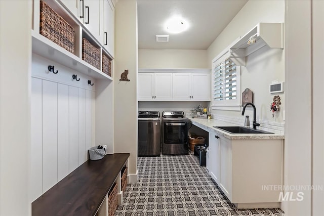 kitchen with sink, white cabinetry, and washing machine and dryer