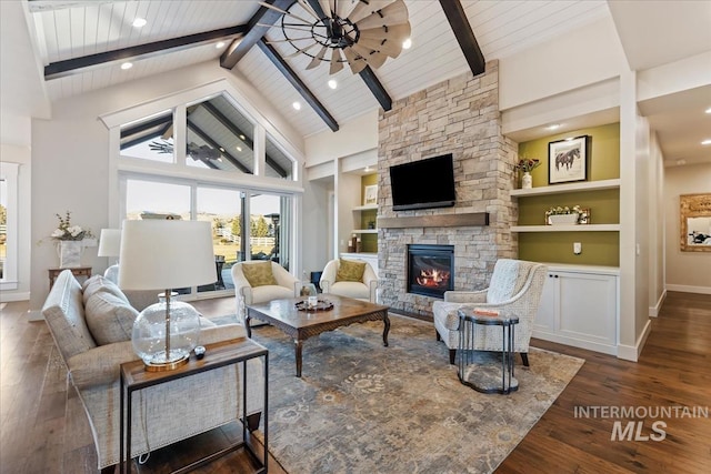 living room featuring ceiling fan, a fireplace, dark hardwood / wood-style floors, beamed ceiling, and built in shelves