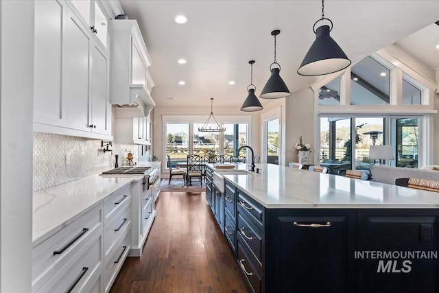 kitchen featuring tasteful backsplash, a spacious island, blue cabinets, pendant lighting, and white cabinets