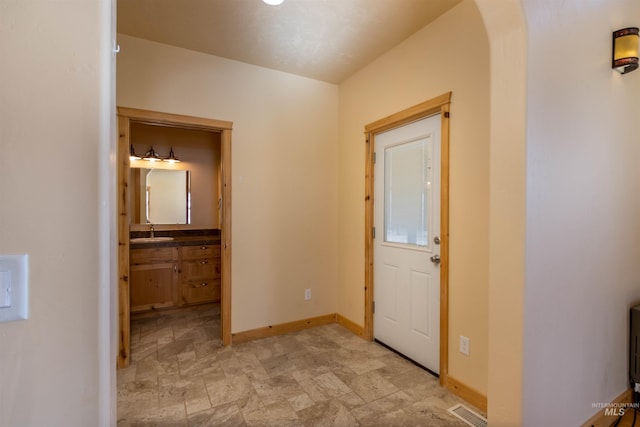 entrance foyer featuring stone finish floor, visible vents, arched walkways, and baseboards