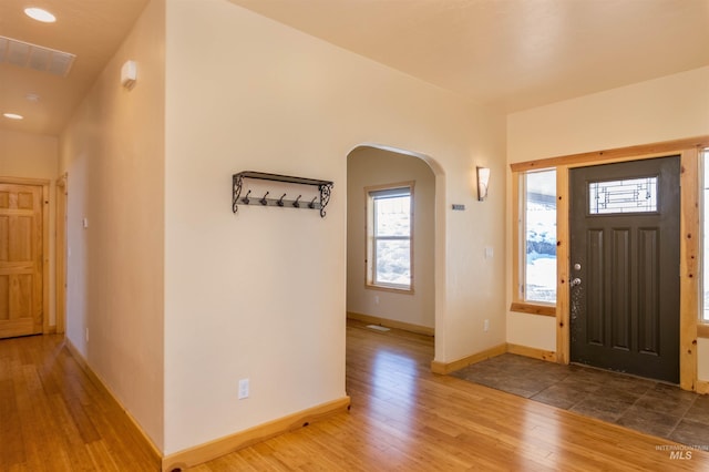 foyer entrance featuring baseboards, visible vents, arched walkways, wood finished floors, and recessed lighting