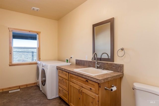 clothes washing area with washing machine and dryer, laundry area, a sink, visible vents, and baseboards