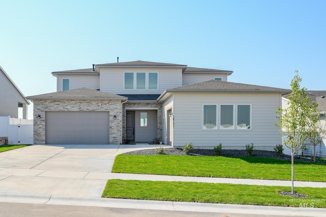 prairie-style home featuring fence, concrete driveway, a front yard, a garage, and stone siding