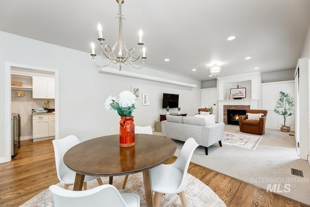 2417 E Brigantine Ct, Eagle, ID 83616 - dining room with light wood-style floors, recessed lighting, a brick fireplace, and a chandelier