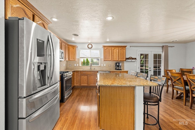 2023 E Wrightwood Dr, Meridian, ID 83642 - kitchen featuring stainless steel appliances, a sink, a kitchen island, light wood-type flooring, and french doors