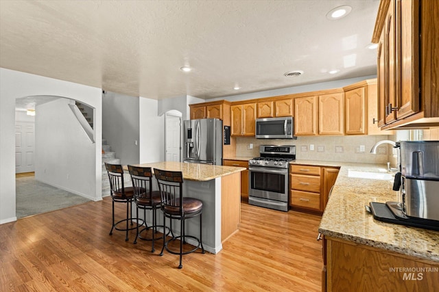 2023 E Wrightwood Dr, Meridian, ID 83642 - kitchen featuring stainless steel appliances, a sink, arched walkways, a kitchen bar, and a center island