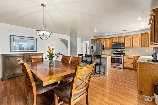 2023 E Wrightwood Dr, Meridian, ID 83642 - dining room featuring arched walkways, light wood-style floors, and a chandelier