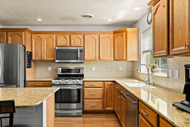 2023 E Wrightwood Dr, Meridian, ID 83642 - kitchen featuring stainless steel appliances, a sink, light wood finished floors, light stone counters, and tasteful backsplash